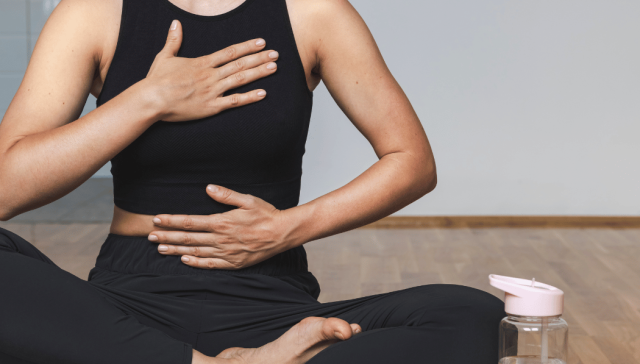 Person seated in a relaxed position using diaphragmatic breathing to practice controlled breath awareness.