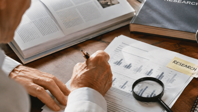 Close-up of research papers, charts, and a magnifying glass on a desk, symbolizing emerging clinical research and scientific evidence.