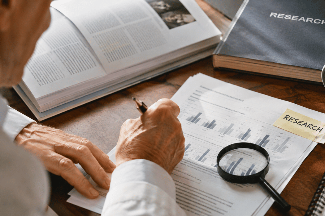 Close-up of research papers, charts, and a magnifying glass on a desk, symbolizing emerging clinical research and scientific evidence.