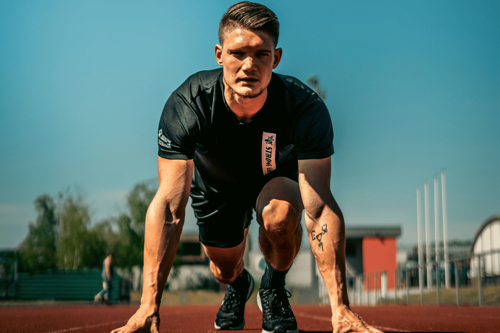 Athlete in a starting position on an outdoor running track preparing to sprint.